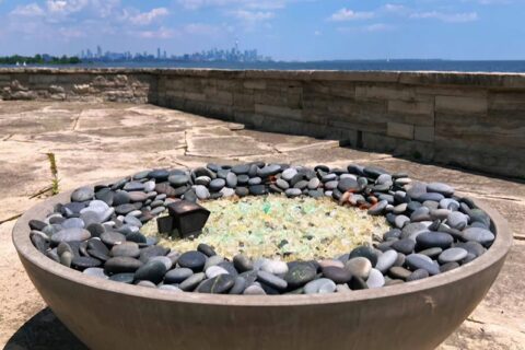 Round fire pit filled with smooth gray stones and glass
