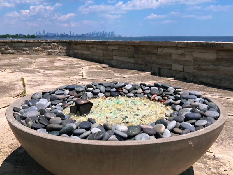 Round fire pit filled with smooth gray stones and glass Round fire pit filled with smooth gray stones and glass