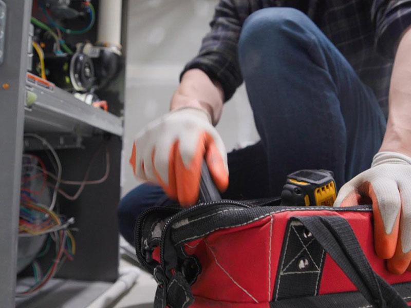A person in gloves kneels by an open electrical panel A person in gloves kneels by an open electrical panel