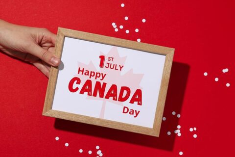 Hand holding a framed sign that reads 1st July Happy Canada Day