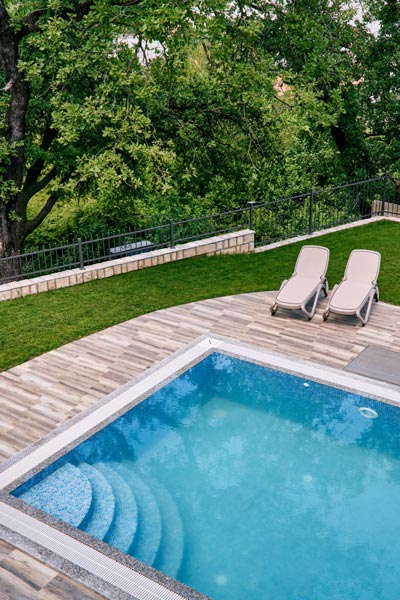 two sun loungers stand next to a rectangular pool two sun loungers stand next to a rectangular pool
